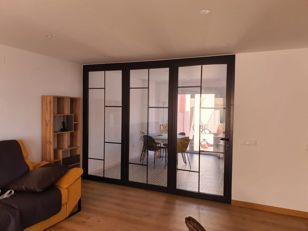 Puerta corredera de cristal con perfiles negros en salón de vivienda moderna