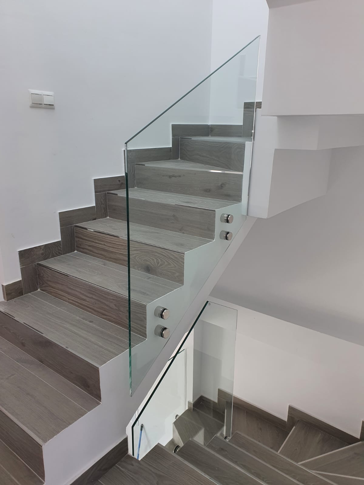 Escalera moderna con peldaños de madera y barandilla de cristal templado
