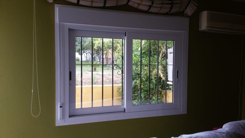 Ventana corredera blanca de PVC con rejas de seguridad desde el interior de la vivienda