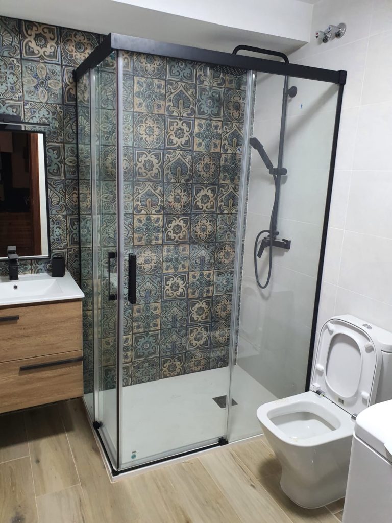 Mampara de ducha corredera en aluminio negro y cristal en baño con azulejos decorativos